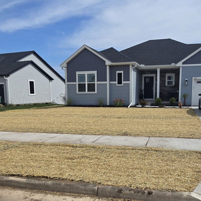 Residential landscaping and grading project with freshly seeded lawn covered in straw outside a newly built home in eastern Wisconsin.